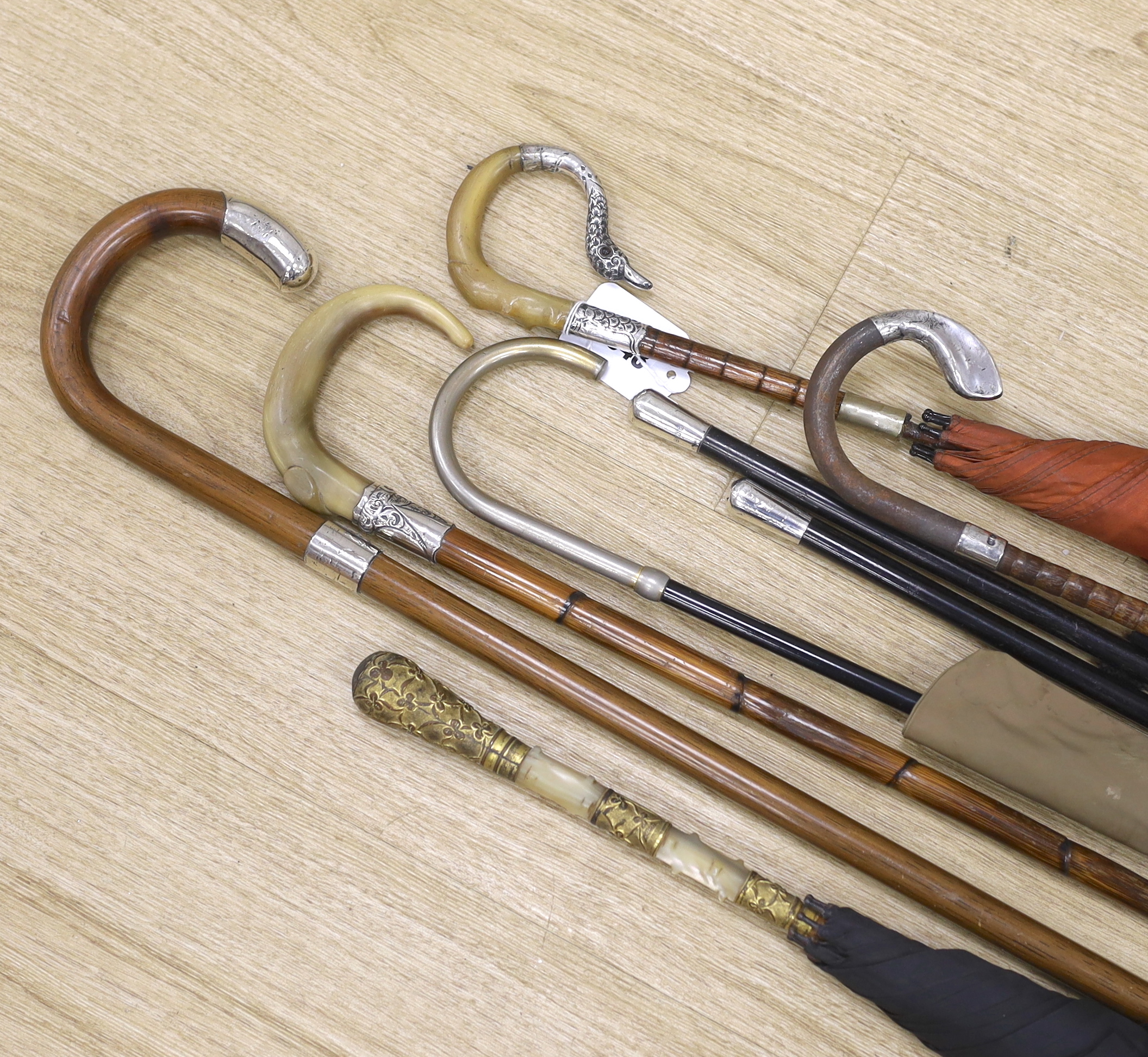 Various vintage umbrellas and walking sticks, three with silver mounted handles and two ebonised swagger sticks with silver tops